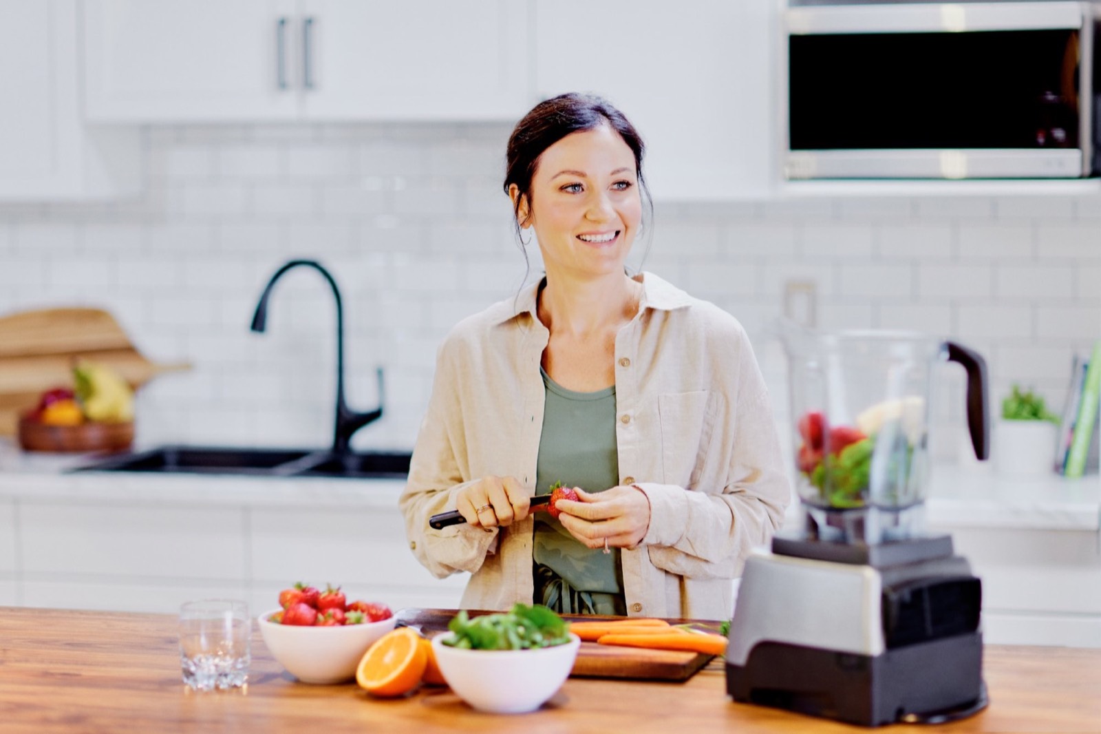 April smiling in her kitchen while slicing fresh strawberries